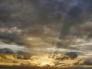 Dramatic sky with sun rays seep through clouds during sunrise