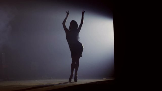 Beautiful female dancer demonstrating her perfect sensual figure and dancing on dark background with strobe light effect . Silouhette of female dancer. Shot on RED HELIUM Cinema Camera in slow motion.