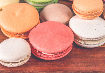 French macarons in cup on wooden background.Toned image