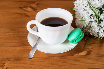 Cup of coffee and French macaroons and a white bouquet of flowers