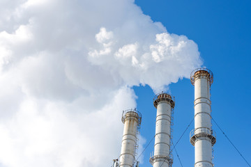 Smoking pipes making clouds against blue sky background. Dioxide air contamination. Environmental pollution