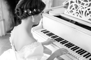 woman playing the piano in a beautiful dress, black and white photo, romantic image