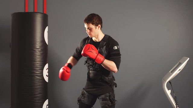 Boxer wearing ems suit training with punching bag.