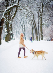 A woman walks with a dog in a winter park