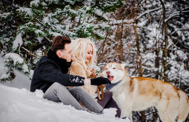 Amazing couple  sitting on the snow near their dog