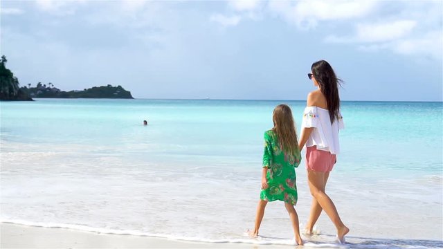 Beautiful mother and daughter on Caribbean beach. Family on beach vacation. SLOW MOTION