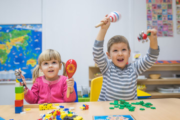 Happy smilinh caucasian children playinh in kindergarten and hands up