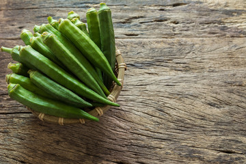 raw okra fruit in bamboo basket on old and crack wooden background with copy space. organic healthy food concept. - obrazy, fototapety, plakaty