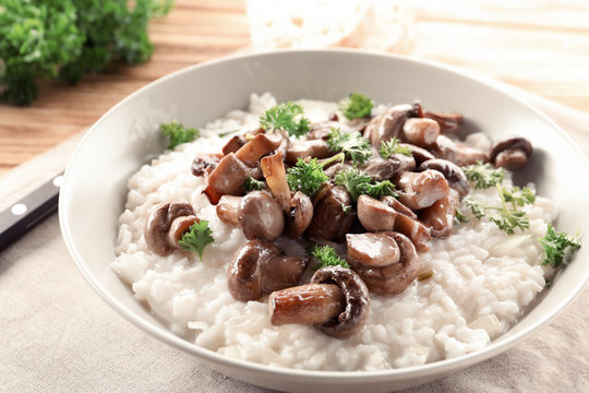 Plate with risotto and mushrooms on table, closeup