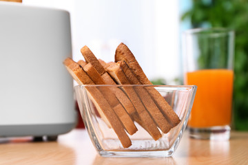 Bowl with toasted bread and glass of juice on table
