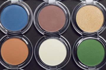 Different eye shadows on dark background. Professional makeup products