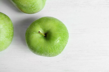 Fresh green apples with water drops on white table, top view