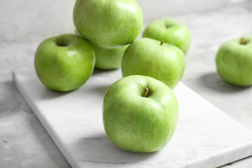 Marble board with fresh green apples on table