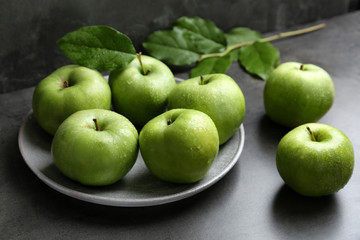 Plate with fresh green apples on table