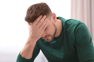Fototapeta premium Young man suffering from headache at home