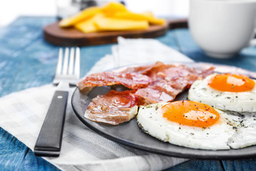 Plate with fried eggs and bacon on table, closeup