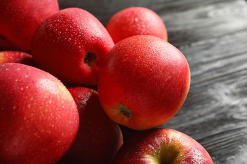 Fresh red apples with drops of water on wooden table, closeup