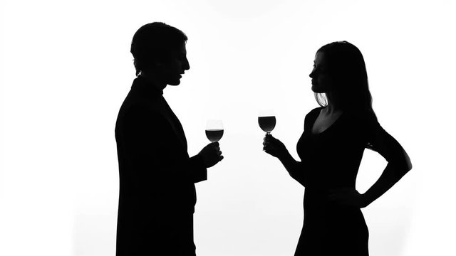 Silhouette of young couple drinking wine, getting acquainted, woman flirting