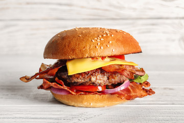 Tasty burger with bacon on wooden table
