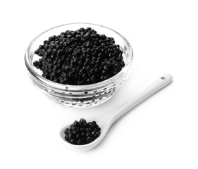 Glass bowl and spoon with black caviar on white background
