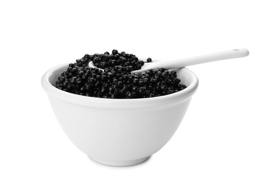 Ceramic bowl and spoon with black caviar on white background