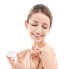 Young woman applying body cream on white background