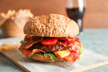 Tasty burger with bacon on wooden board