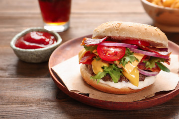 Plate with tasty bacon burger on table