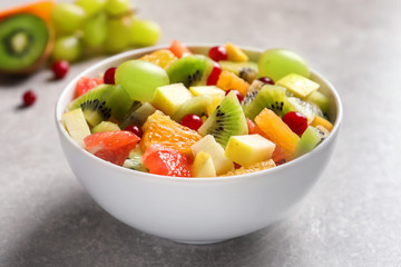 Bowl with fresh fruit salad on grey background