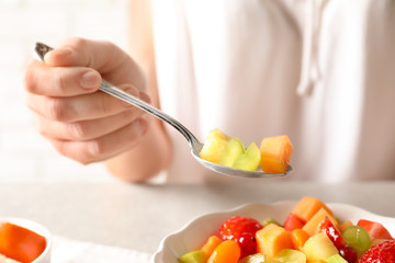 Woman with bowl of fresh fruit salad, closeup