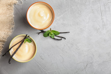 Cups with vanilla pudding, sticks and fresh mint on light background - obrazy, fototapety, plakaty