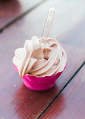 Soft serve ice cream sundae with chocolate flavour in pink plastic container
