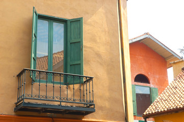 Fototapeta na wymiar Open green wood window on old wall with balcony