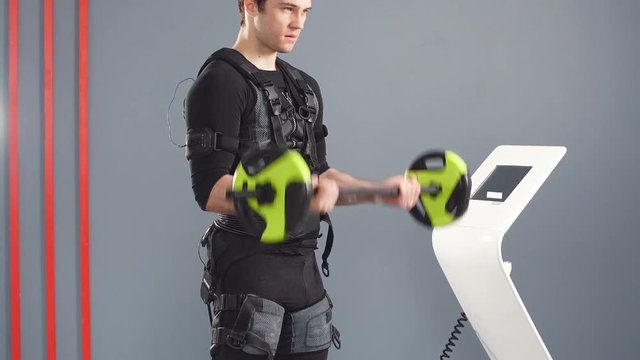 Man wearing electrostimulation suit working out EMS training with barbell.