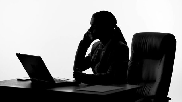 Silhouette of irritated businesswoman talking on phone, arguing with partners