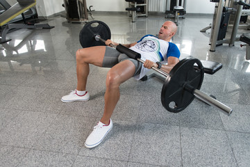 Fototapeta na wymiar Man Exercising Legs With Barbell In The Gym