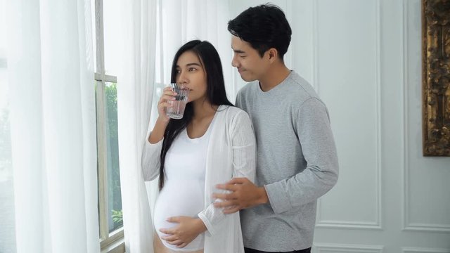 Young husband take care his pregnant wife with drink water