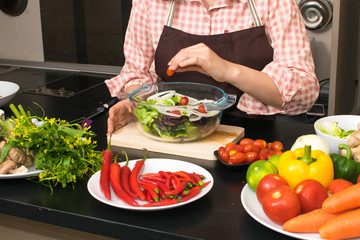 beautiful woman cooking in new kitchen making healthy food with vegetables.
