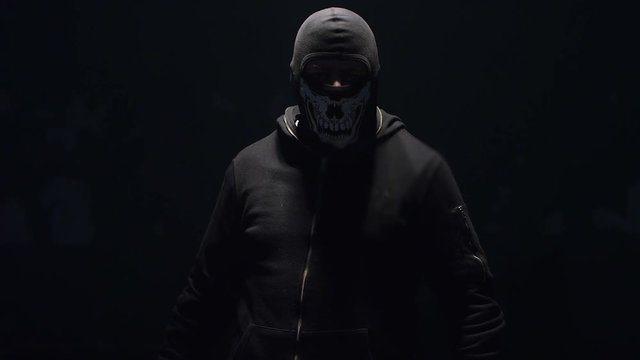 Portrait of masked hooligan with baseball bat on black background . Shot on RED cinema camera .