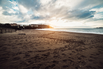 Foot prints on the ocean beach sand at sunset time.