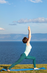 Fototapeta na wymiar Young woman doing yoga at seaside