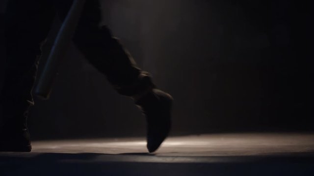 Man's legs walking on dark room. Man with baseball bat. Shot on RED Cinema Camera in slow motion