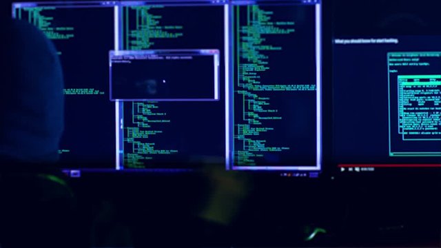 Hacker with mask breaking code. Hacker with mask using computers to crack the internet from hackers dark room. Hackers face seen from the screen.Shot on RED Cinema Camera