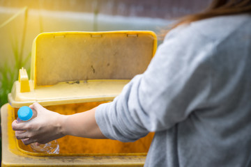 Woman hand put empty drinking water bottle in separate trash. Disposal garbage management Environmental care concept, Close up.