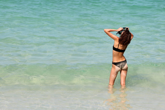 Tourists teenage girl enjoying to use the snorkel on the beach.