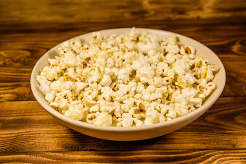 Ceramic plate with popcorn on wooden table