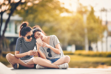 Two women friends sit in the park and relax on a happy holiday.