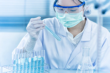 Asian women scientist with test tube making research in clinical laboratory.Science, chemistry, technology, biology and people concept