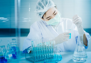Asian women scientist with test tube making research in clinical laboratory.Science, chemistry, technology, biology and people concept