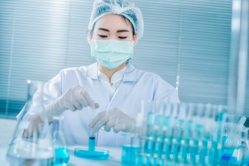 Asian women scientist with test tube making research in clinical laboratory.Science, chemistry, technology, biology and people concept